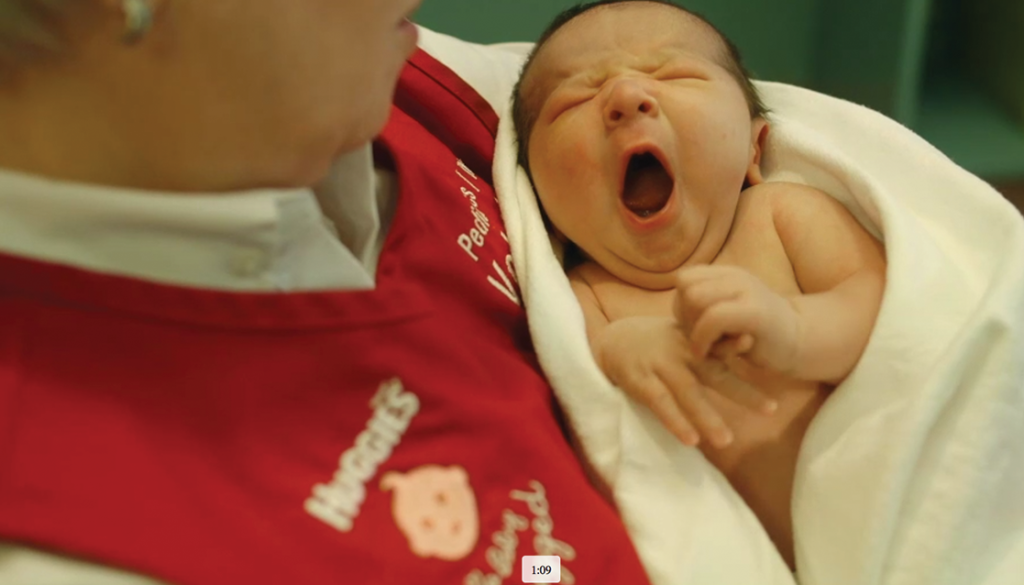 Baby yawning while being held by a Huggies volunteer hugger